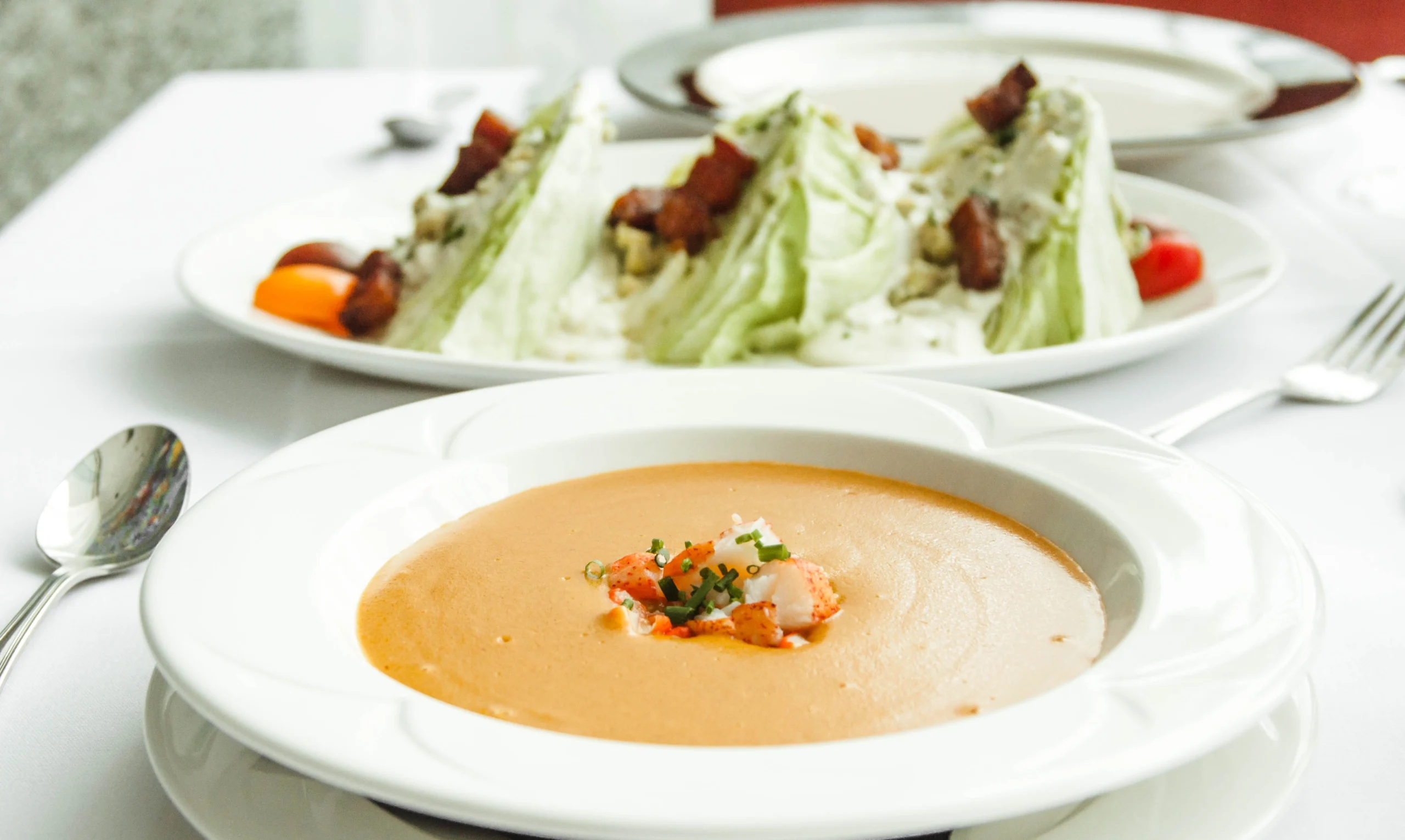 A bowl of lobster bisque and a wedge salad