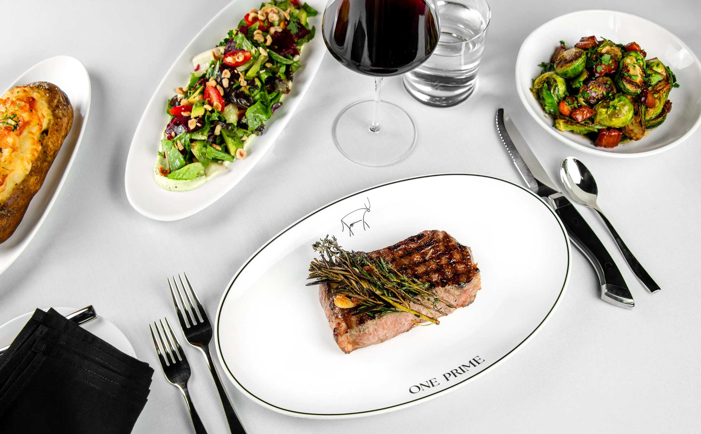 A full meal at One Prime including steak, salad, vegetables, and baked potato